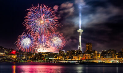 Fireworks over Seattle skyline at night with the Space Needle illuminated near the center.