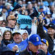 Crowd of Seattle Mariners fans cheering in a stadium, waving blue towels and banners.