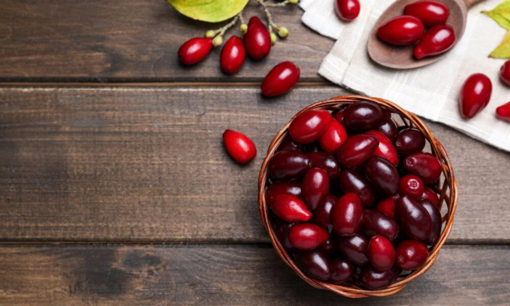 Basket filled with red cherries on a dark wooden table; a few loose cherries nearby.