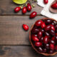 Basket filled with red cherries on a dark wooden table; a few loose cherries nearby.