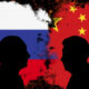 Two black silhouettes face off against a background blending the Russian flag on the left and the Chinese flag on the right, with fiery edges suggesting tension.