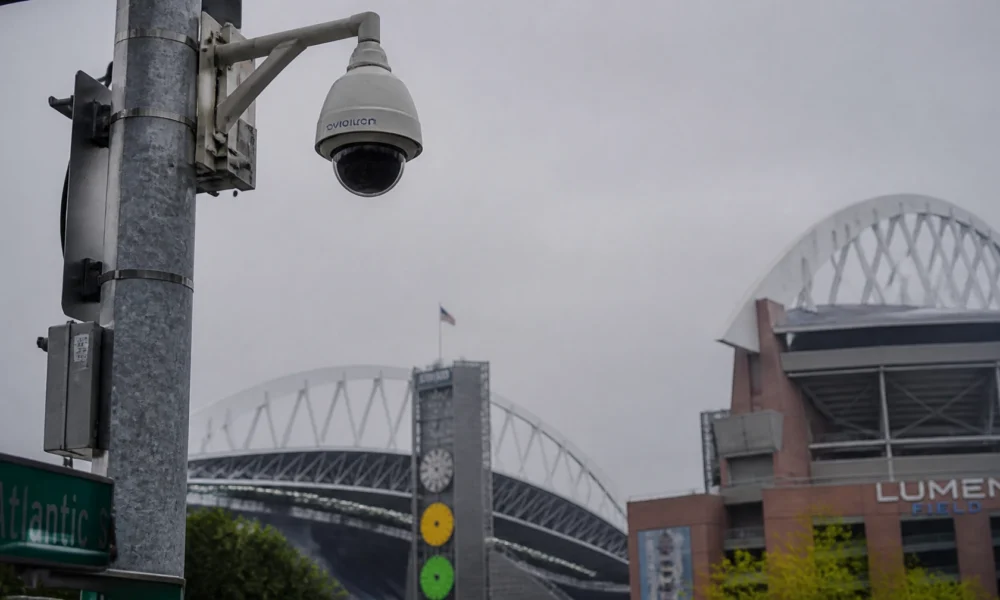 Security camera mounted on a metal pole overlooking Lumen Field stadium with the arena’s arch in the background.