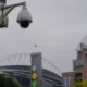 Security camera mounted on a metal pole overlooking Lumen Field stadium with the arena’s arch in the background.