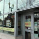 Exterior of a Vietnamese restaurant with large glass windows, menu posters, and a lit OPEN sign outside a brick building.