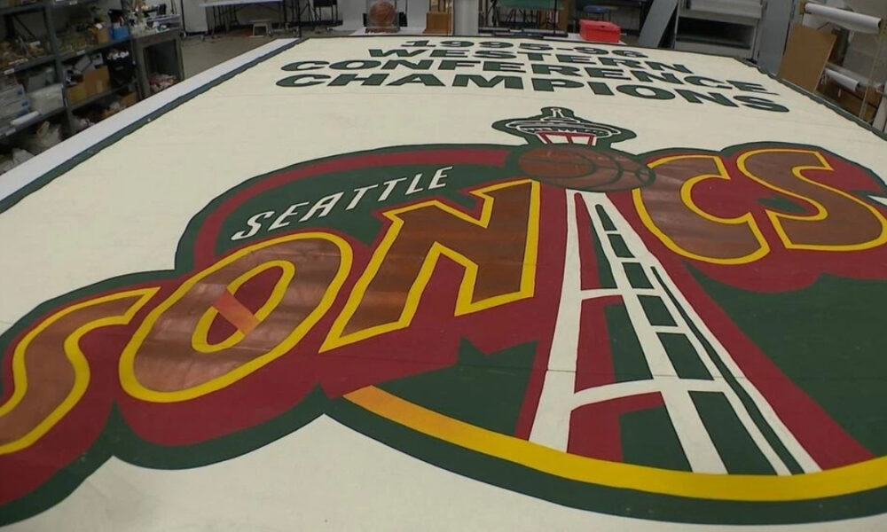 A large Seattle SuperSonics floor logo painted on a workshop floor, with the word SONICS and a space‑needle emblem in the foreground.