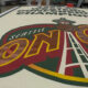 A large Seattle SuperSonics floor logo painted on a workshop floor, with the word SONICS and a space‑needle emblem in the foreground.