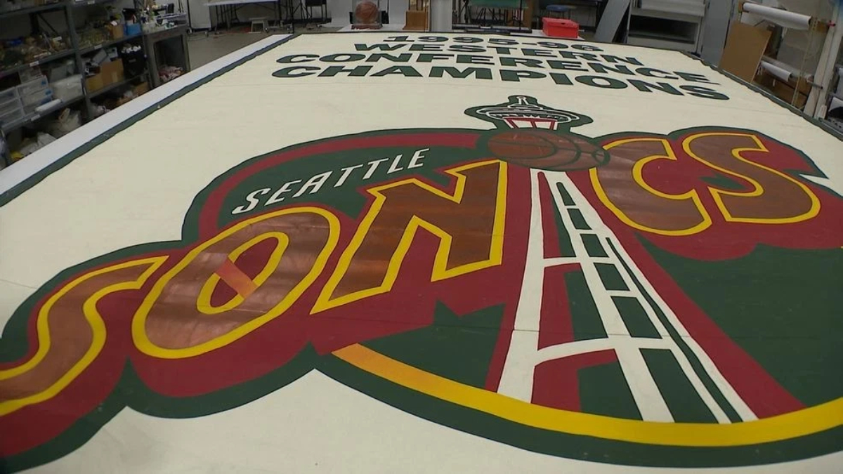 A large Seattle SuperSonics floor logo painted on a workshop floor, with the word SONICS and a space‑needle emblem in the foreground.