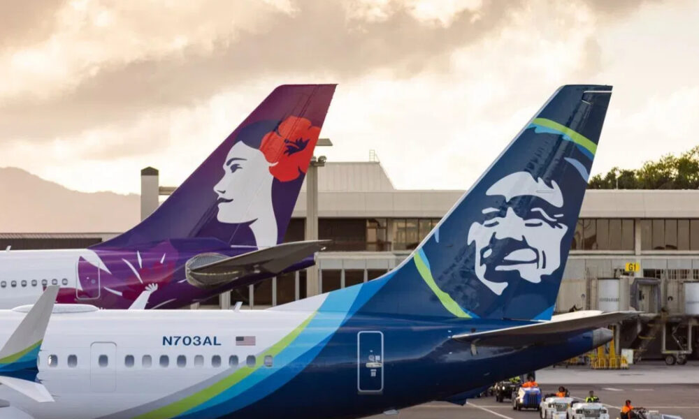 Two Alaska Airlines jets at the gate with vibrant tail art—one tail shows a woman’s profile, the other a stylized face, against a bright airport backdrop.
