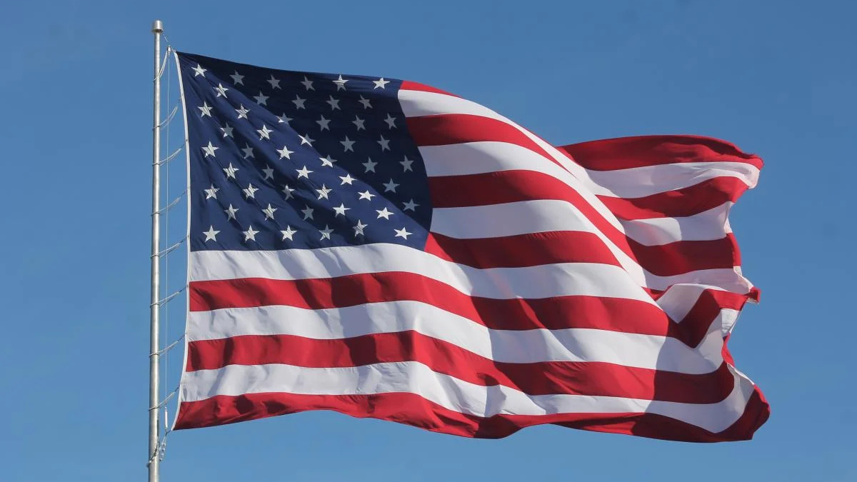American flag waving on a flagpole against a clear blue sky.