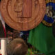 Woman speaks at a City of Seattle press conference podium, with American flag and large seal backdrop; a police officer stands to the right.