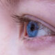 Close-up of a blue eye with long eyelashes and pale skin around it.