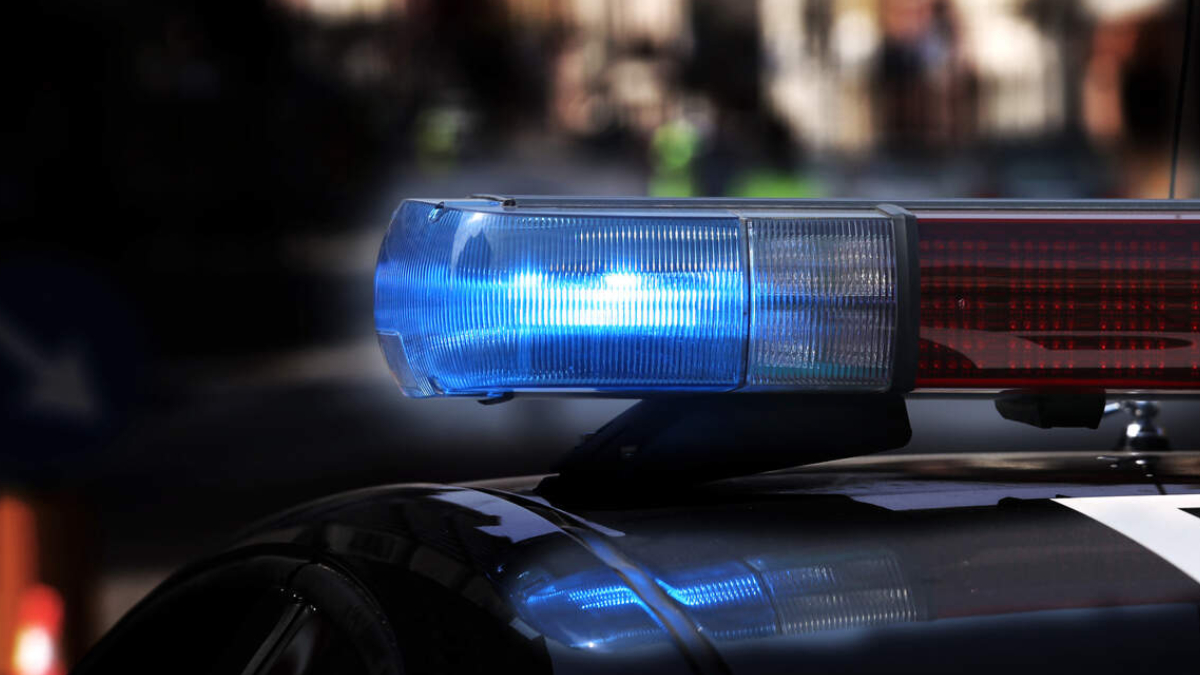 Blue and red police car emergency light bar on the roof, flashing against a dark background.