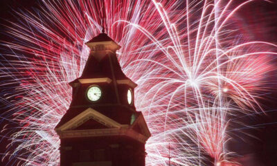 Clock tower at night with colorful fireworks bursting behind it.
