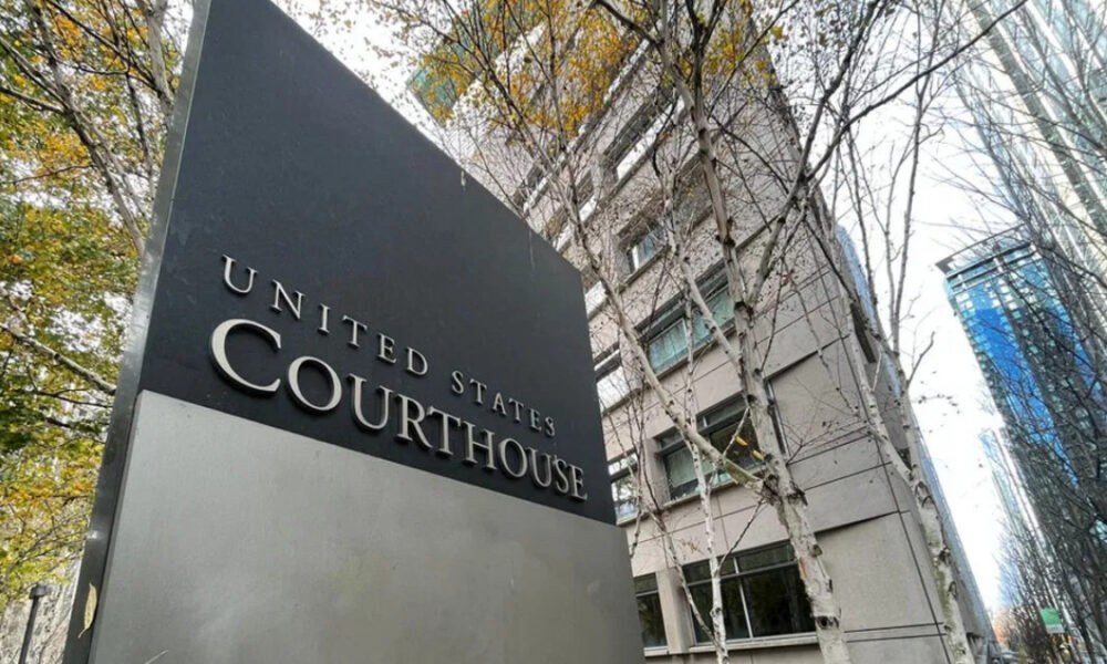 Exterior view of a courthouse sign reading 'United States Courthouse' beside a modern grey building with bare trees in autumn.