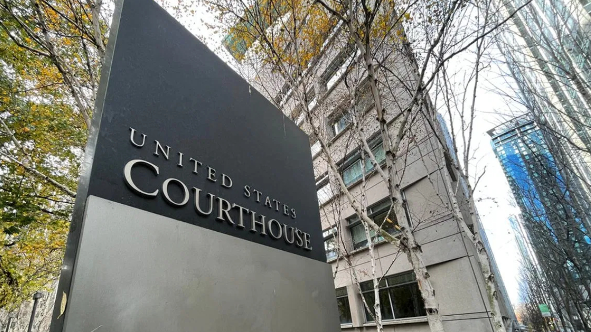 Exterior view of a courthouse sign reading 'United States Courthouse' beside a modern grey building with bare trees in autumn.