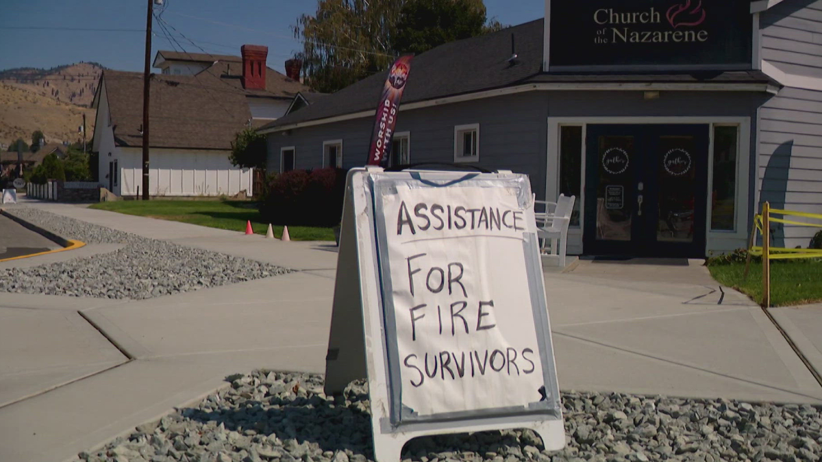 A-frame sign outside a church reads 'ASSISTANCE FOR FIRE SURVIVORS' offering help to fire victims.