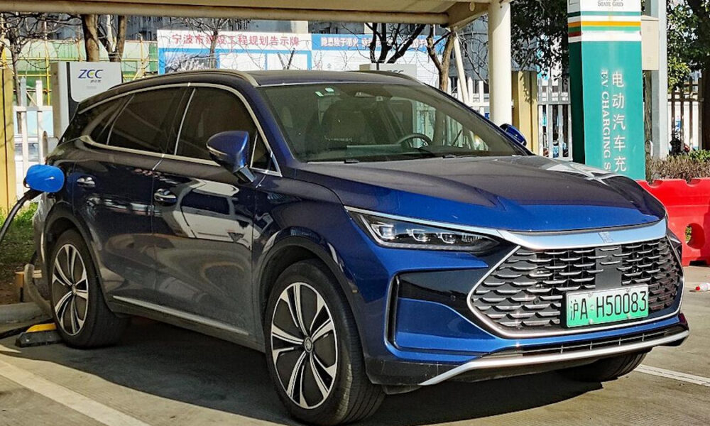 Blue electric SUV being charged at a station, front three-quarters view in a parking lot with a green license plate in Chinese characters.