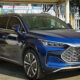 Blue electric SUV being charged at a station, front three-quarters view in a parking lot with a green license plate in Chinese characters.