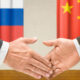 Handshake between two people in front of Russia and China flags, symbolizing international diplomacy and agreement.