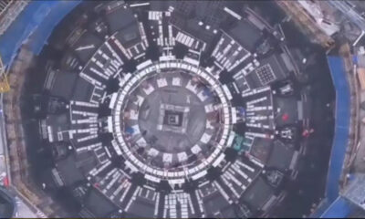 A top-down view of a large circular construction site with concentric rings and white panel modules around the ring.
