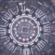 A top-down view of a large circular construction site with concentric rings and white panel modules around the ring.