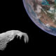 Cratered asteroid in foreground with Earth visible in the upper-right, space around.