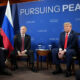 Group of world leaders seated in a panel with flags and a blue backdrop reading 'Pursuing Peace'.