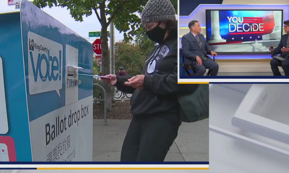 Voter in a knit cap and mask drops a ballot into a blue ballot drop box; inset shows a news set with 'YOU DECIDE'.
