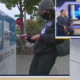 Voter in a knit cap and mask drops a ballot into a blue ballot drop box; inset shows a news set with 'YOU DECIDE'.