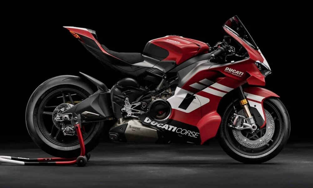 Red Ducati sport motorcycle on a rear stand against a black studio backdrop with white accents on the fairings.