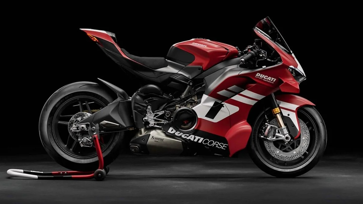 Red Ducati sport motorcycle on a rear stand against a black studio backdrop with white accents on the fairings.