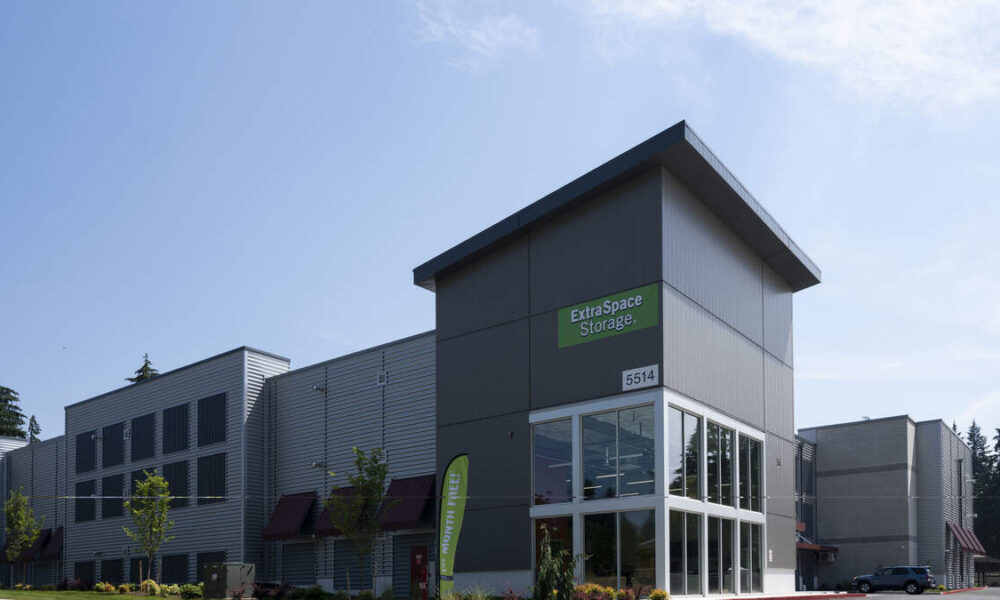 Exterior of an Extra Space Storage facility with gray metal panels and a large glass entrance.