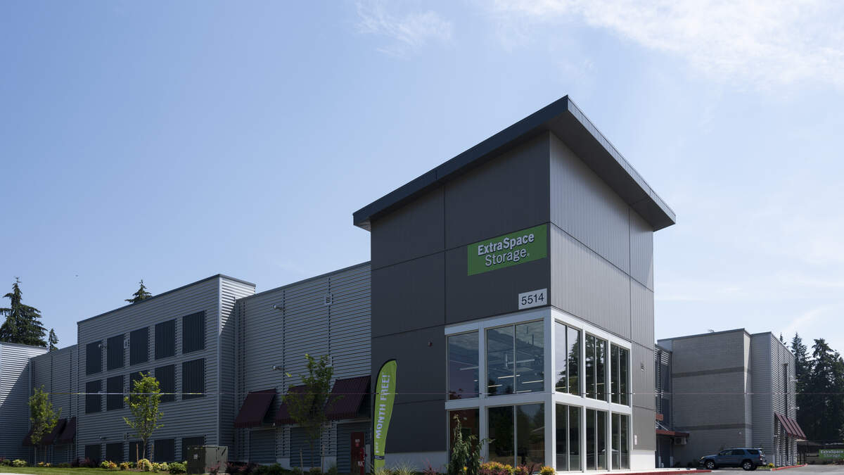 Exterior of an Extra Space Storage facility with gray metal panels and a large glass entrance.