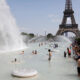 People wading in a large fountain with water jets, Eiffel Tower in the background on a sunny day in Paris tranquilly unfolding the scene nearby parkgoers.