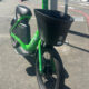 Bright green Lime bike with front basket parked at a curb on a city sidewalk (bike-share bicycle).