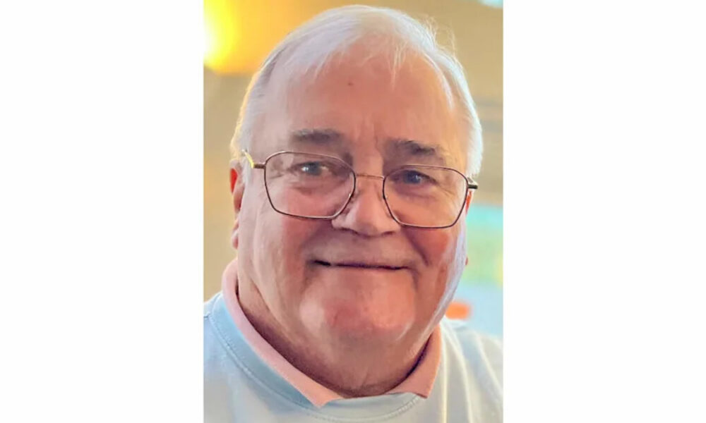 Close-up of an elderly man with white hair and glasses, smiling warmly.