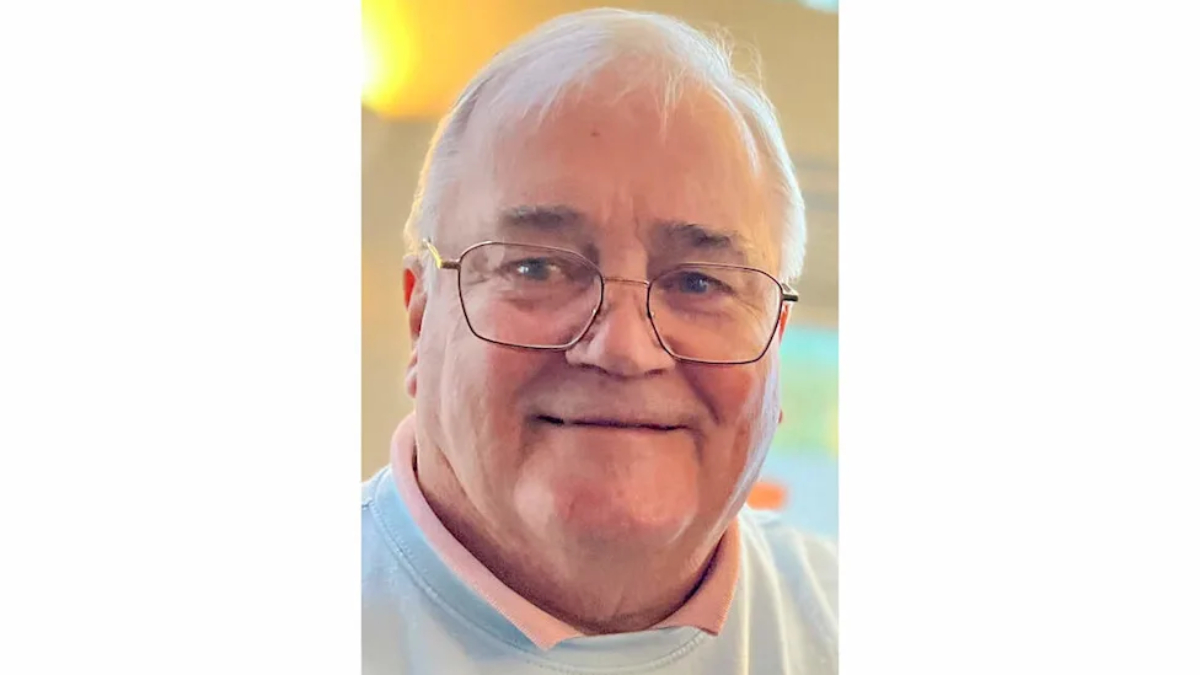 Close-up of an elderly man with white hair and glasses, smiling warmly.