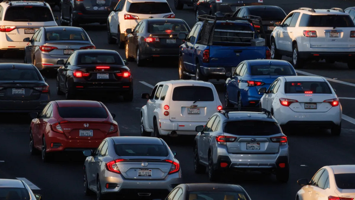 Heavy urban freeway traffic with many cars bumper-to-bumper in multiple lanes.