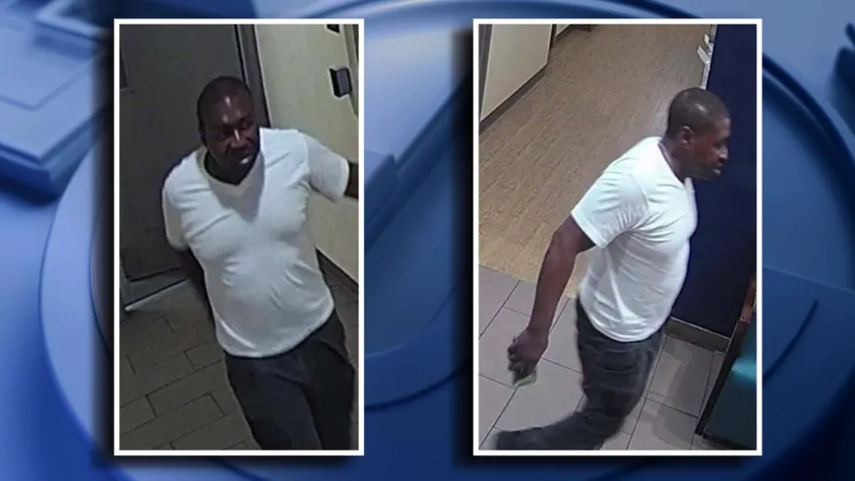 Two side-by-side surveillance photos of a man in a white T‑shirt and dark pants, in a building hallway. In the left image he stands near a door; in the right image he walks down a tiled corridor holding a small item in his left hand.