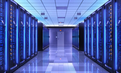 Data center corridor with tall server racks glowing blue and a reflective floor