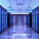 Data center corridor with tall server racks glowing blue and a reflective floor