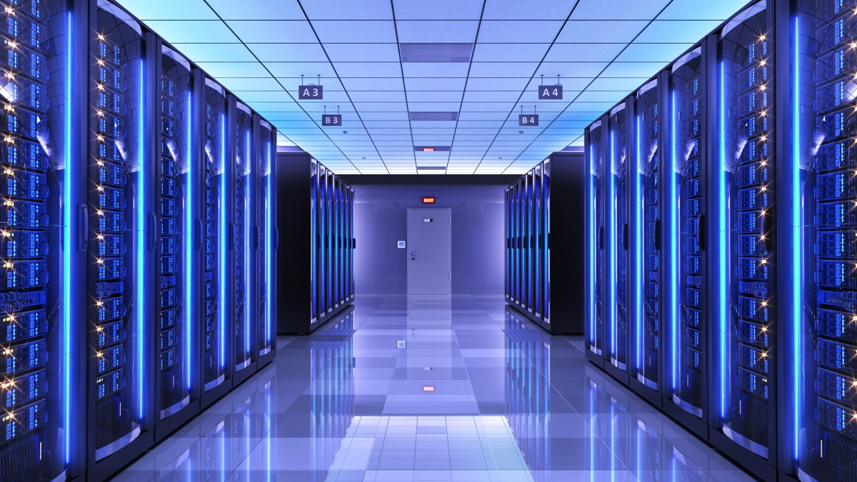 Data center corridor with tall server racks glowing blue and a reflective floor