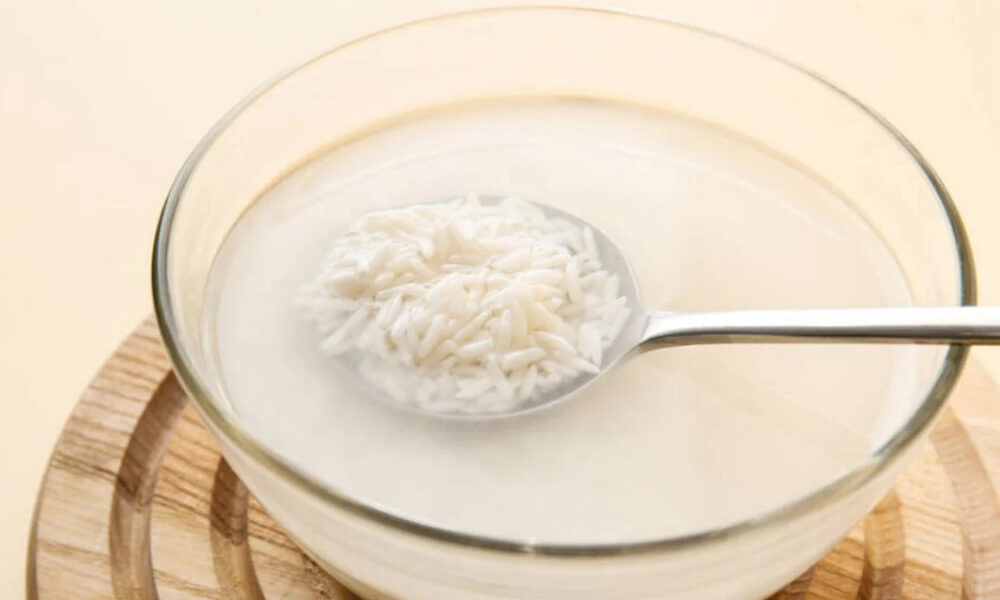 Bowl of white rice porridge (congee) with a metal spoon resting in the liquid.
