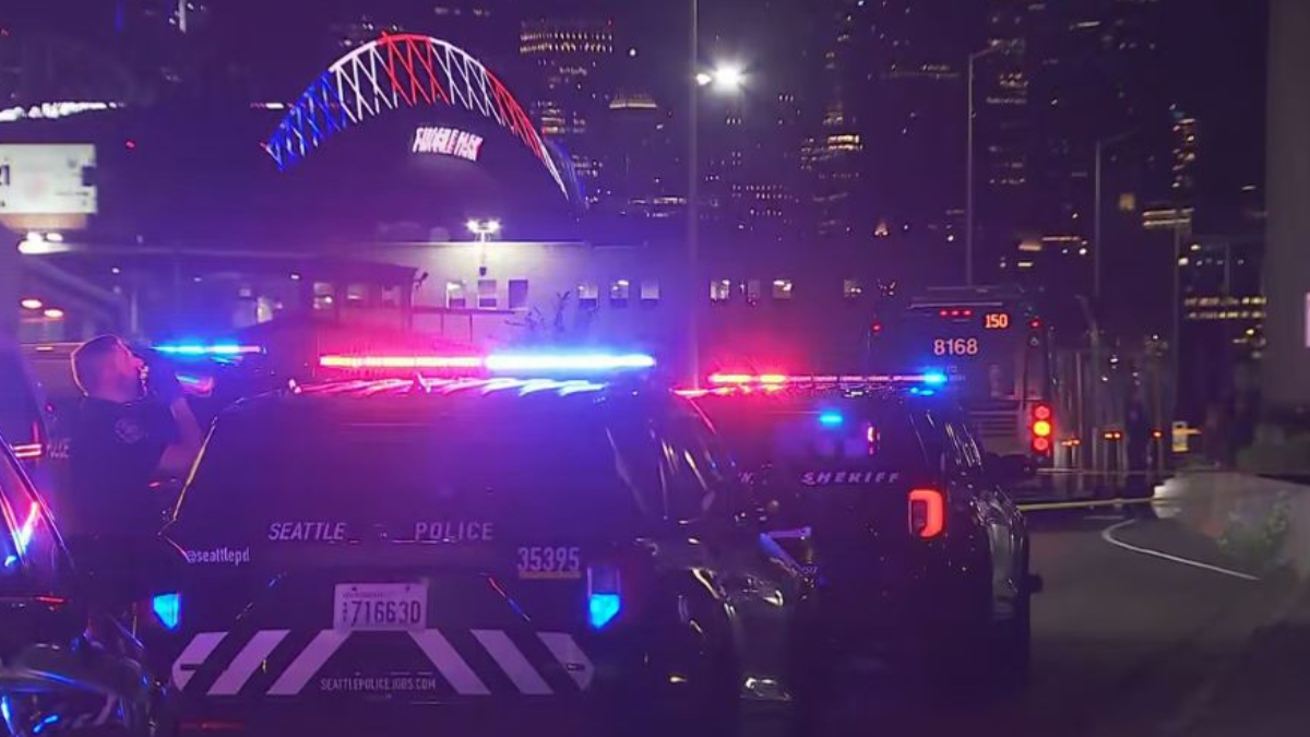 Seattle police cars with flashing red and blue lights at night in an urban area.