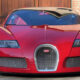 Front view of a red Bugatti sports car parked on a driveway with brick walls in the background, showing a distinctive horseshoe grille and sleek headlamps.