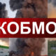 Collage of thick black smoke rising from industrial buildings with a red geometric banner reading 'КОБМО' across the center.