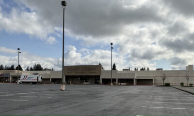 Hobby Lobby store in a strip mall with a mostly empty parking lot and a moving truck parked to the left under a cloudy sky