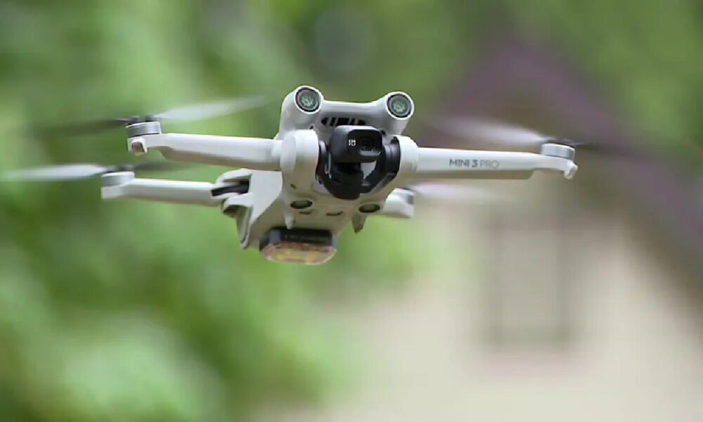 DJI Mini 3 Pro drone flying outdoors with a blurred green background in flight.