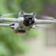 DJI Mini 3 Pro drone flying outdoors with a blurred green background in flight.