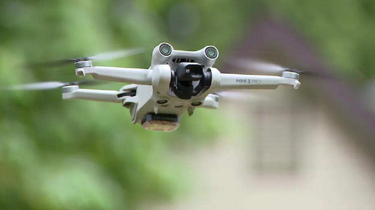 DJI Mini 3 Pro drone flying outdoors with a blurred green background in flight.